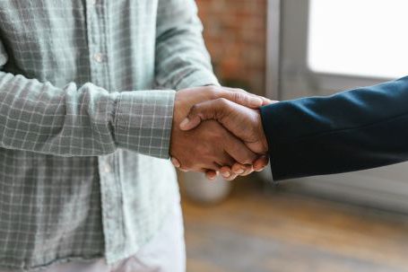 Networking, Collaboration - A Person in Green Plaid Long Sleeve Shirt Shaking Hands with Person in Black Blazer